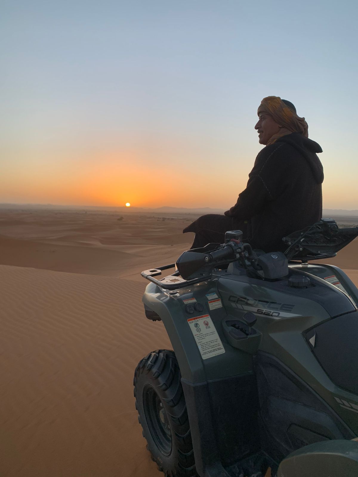 Traveller riding a quad bike at sunset in the Moroccan desert